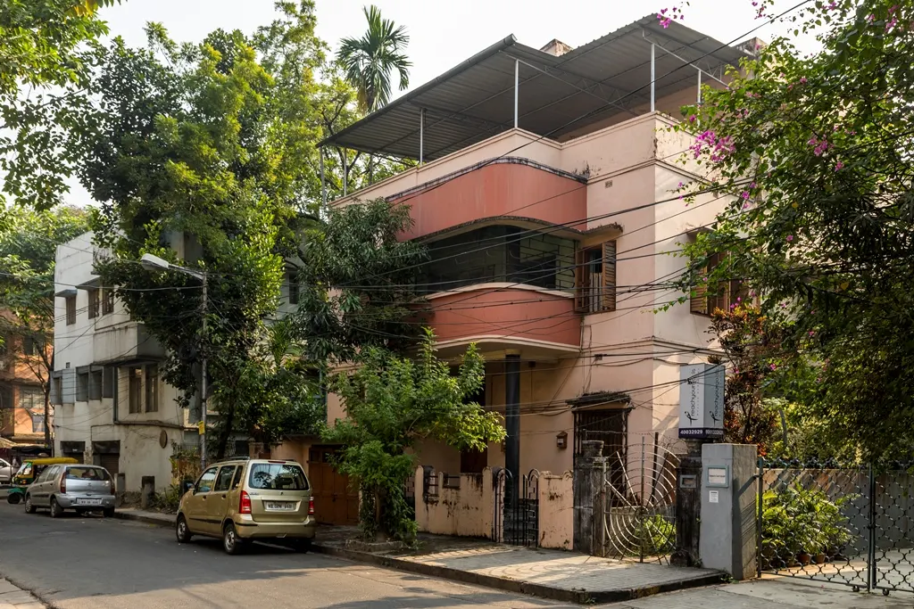 An art-deco style pink building on a street in Kolkata.