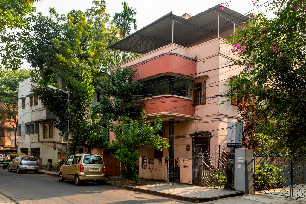 An art-deco style pink building on a street in Kolkata.