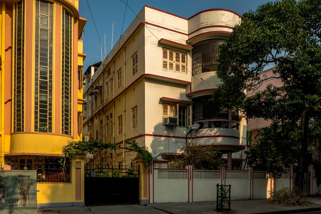 An art-deco style yellow and white building on a street in Kolkata.