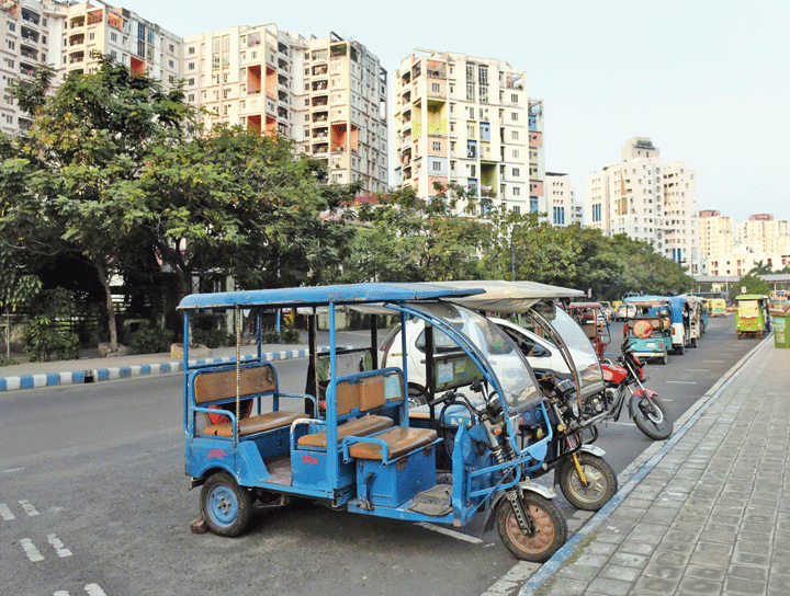 A series of e-rickshaws parked on the side of the road.